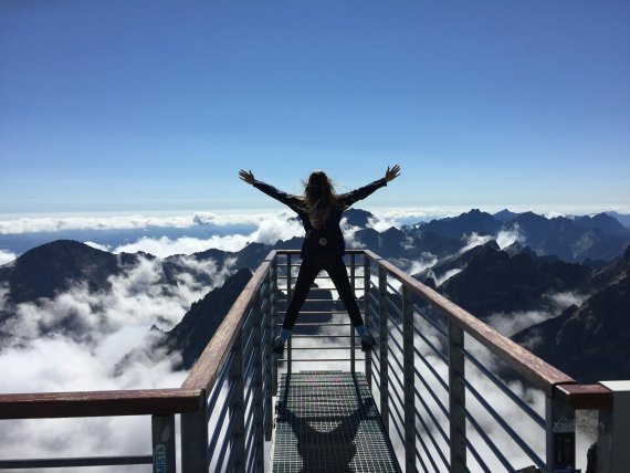 Eine Frau steht auf einer Aussichtsplattform über den Wolken.