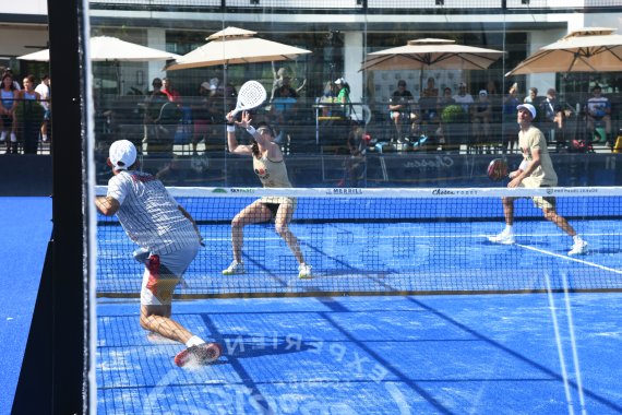 Drei Personen spielen Padel auf blauem Court